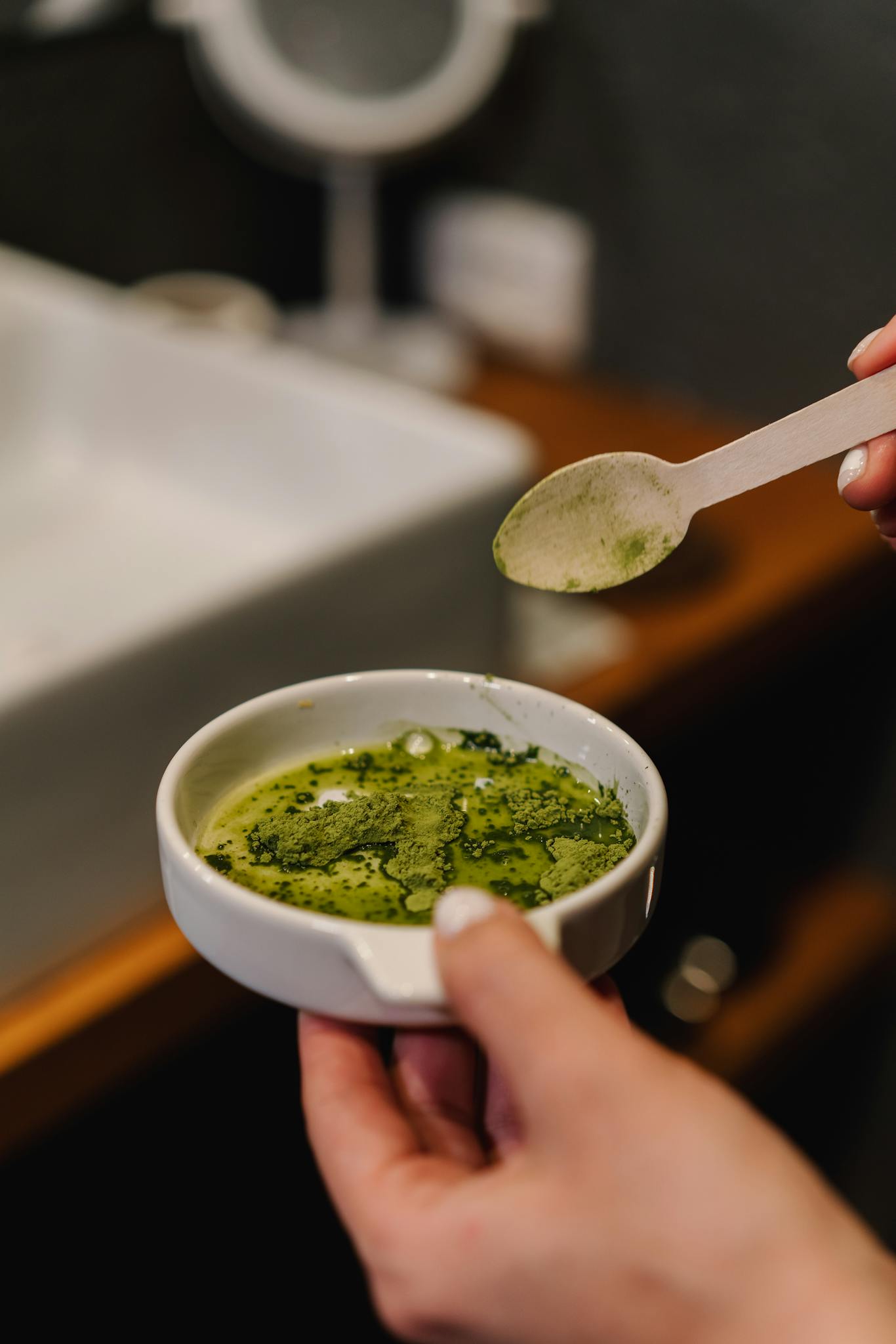 A person prepares matcha tea in a modern bathroom, capturing a calming home ritual.